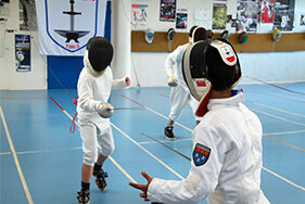 Deux enfants s'entraînant en tenue d'escrime épée à la main