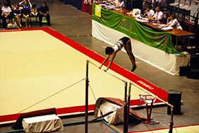 Jeune fille effectuant un saut sur barres asymétriques lors d'une compétition